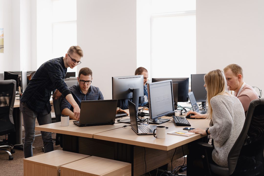 Team of young professionals collaborating in a modern office environment, supported by managed IT help desk services