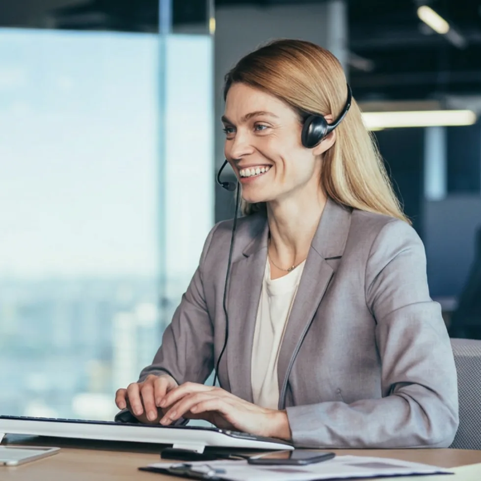 female tech support specialist helping a client over the phone with a headset on.